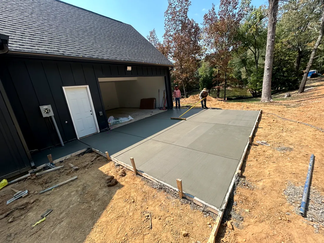 Fresh garage apron poured at a dark-sided barn-style building