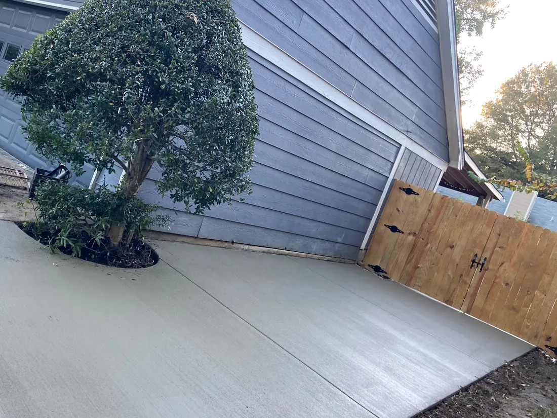 Fresh curved patio poured around a preserved shrub beside a house